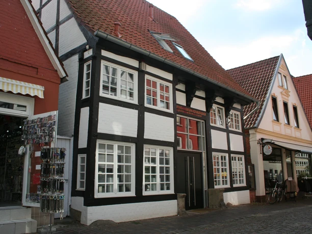 Ein traditionelles Fachwerkhaus mit weißer Fassade und schwarzem Gebälk in der Weserstraße Nienburg.