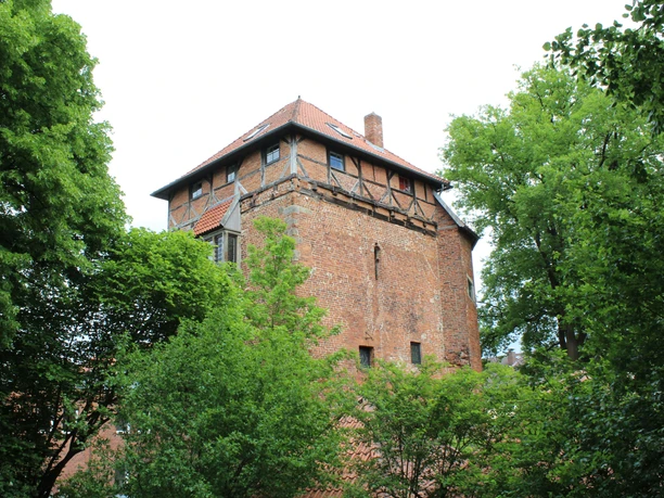 Stockturm Nienburg Backsteinturm in grünbewachsener Umgebung, historische Architektur mit Fachwerkelementen und Schrägdach.