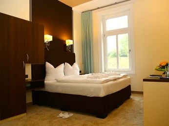 Ein modernes Hotelzimmer mit einem großen Doppelbett, weichen Kissen und stilvoller Beleuchtung.