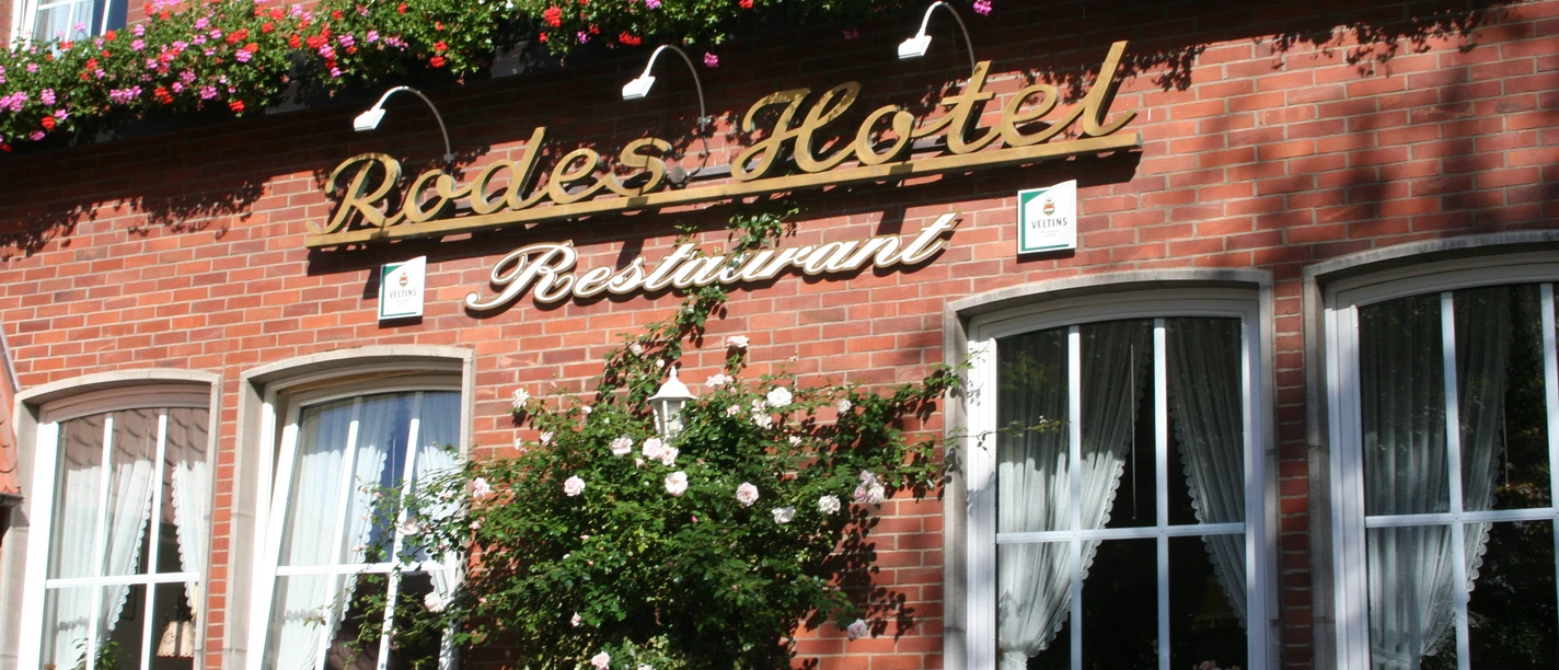 Red brick building decorated with flowers, including the lettering "Rodes Hotel Restaurant".