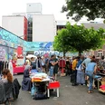 Flea market at the old fire station Besucher stöbern auf einem belebten Flohmarkt im Freien, umgeben von Streetart und Gebäuden.Visitors browse through a lively outdoor flea market surrounded by street art and buildings.