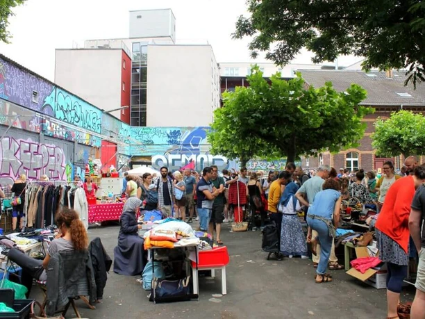 Flea market at the old fire station Visitors browse through a lively outdoor flea market surrounded by street art and buildings.