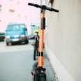 pexels-markus-spiske-3671151.jpg Ein oranges Elektromoped steht auf einem Gehweg, angelehnt an eine Hauswand in einer städtischen Umgebung.