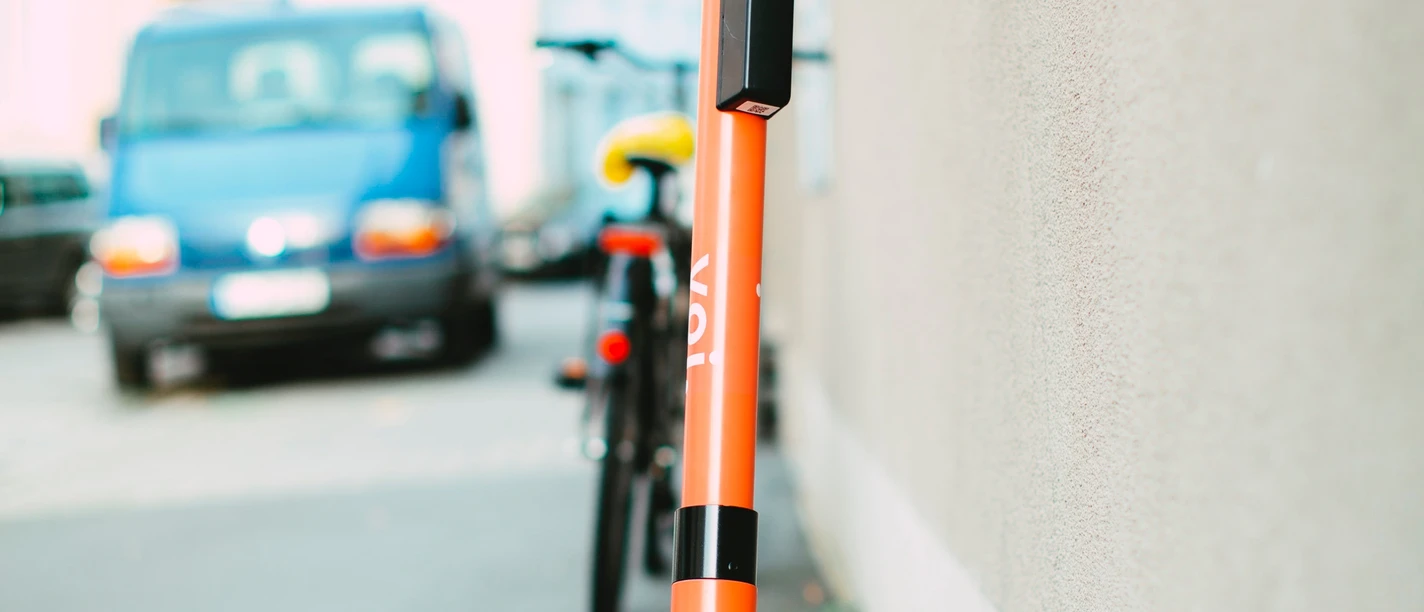 pexels-markus-spiske-3671151.jpg Ein oranges Elektromoped steht auf einem Gehweg, angelehnt an eine Hauswand in einer städtischen Umgebung.