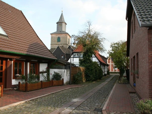 Fischerviertel mit Martinskirche Hoya Kopfsteingepflasterte Gasse in Hoya mit Fachwerkhäusern und der Martinskirche im Hintergrund.