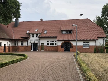 Ehemaliges Schulgebäude mit rotem Ziegeldach, strahlt traditionelles Flair und erhabene Struktur aus.