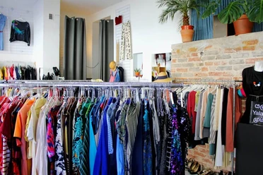 Kleiderei Interior view of a boutique with colorful clothes on clothes racks and decorative plants.