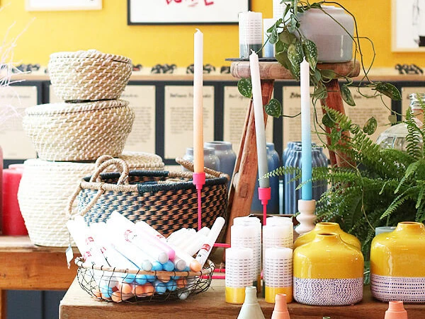 Schee Das Bild zeigt eine farbenfrohe Wand mit verschieden gerahmten Kunstwerken. Im Vordergrund stehen dekorative Kerzenständer, Strickkörbe und Vasen, die zusammen eine kreative und lebendige Atmosphäre erzeugen.The picture shows a colorful wall with various framed works of art. In the foreground are decorative candlesticks, knitted baskets and vases, which together create a creative and lively atmosphere.