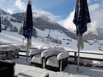 Terrace with snow Restaurantterasse mit verschneiten Gartenmöbeln und Blick auf den SesselliftRestaurant terrace with snow-covered garden furniture and view of the chairliftTerrasse du restaurant avec meubles de jardin enneigés et vue sur le télésiège