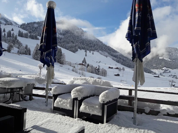 Terrasse avec neige Terrasse du restaurant avec meubles de jardin enneigés et vue sur le télésiège