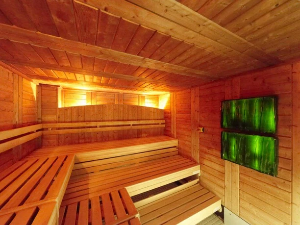 Agrippa bath Wood-clad sauna with two green lights, warmly lit, cozy and inviting.