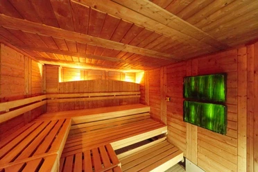 Agrippabad Holzverkleidete Sauna mit zwei grünen Leuchten, warm erleuchtet, gemütlich und einladend.