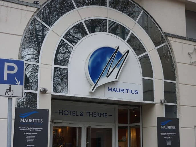 Mauritius Hotel und Therme Eingang zu Mauritius Hotel & Therme mit überdachtem Bogen und markantem blauen Logo.Entrance to Mauritius Hotel & Therme with covered arch and striking blue logo.