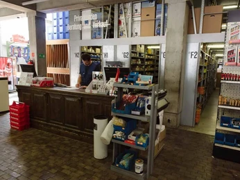 Hülden Ein Baumarkt mit einer Vintage-Theke, Metallregalen, Schrauben und einem Verkäufer hinterm Tresen.A DIY store with a vintage counter, metal shelves, screws and a salesman behind the counter.