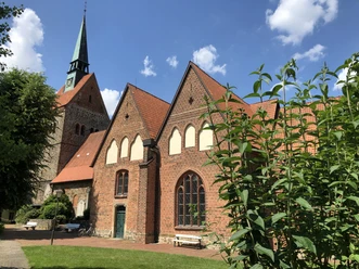 Kirche Vilsen Backsteinkirche in sommerlicher Umgebung mit Fachwerkelementen und einem markanten Kirchturm.