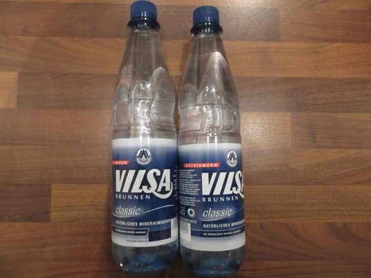 Vilsa Zwei Plastikflaschen Vilsa Brunnenwasser stehen auf einer dunklen Holzoberfläche nebeneinander.Two plastic bottles of Vilsa fountain water stand next to each other on a dark wooden surface.To plastikflasker med Vilsa-springvand står ved siden af hinanden på en mørk træoverflade.Twee plastic flessen Vilsa fonteinwater staan naast elkaar op een donker houten oppervlak.
