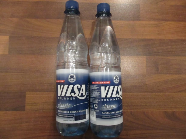Vilsa Zwei Plastikflaschen Vilsa Brunnenwasser stehen auf einer dunklen Holzoberfläche nebeneinander.