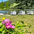 Wohnmobilhafen und Campingplatz am SchiederSee Wohnmobile stehen am Ufer eines Sees, umgeben von grüner Natur und blühenden Blumen im Vordergrund.
