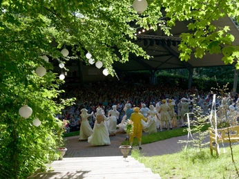 Freilichtbühne in Bökendorf Freilichtbühne Bökendorf: Menschengruppen genießen eine Theateraufführung unter freiem Himmel im Grünen.