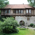 Historisches Gebäude mit Fachwerk, umgeben von Garten und kleiner Terrasse mit Bank und Tisch.