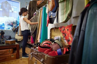 Vintage Emde In einem Vintage-Laden stöbert eine Person konzentriert durch bunte Kleidungsstücke und Accessoires.