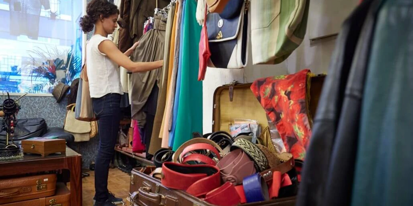 Vintage Emde In einem Vintage-Laden stöbert eine Person konzentriert durch bunte Kleidungsstücke und Accessoires.In a vintage store, a person is browsing through colorful clothing and accessories.