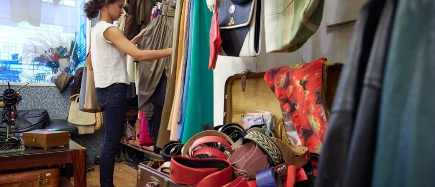 Vintage Emde In a vintage store, a person is browsing through colorful clothing and accessories.