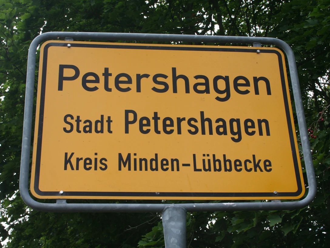 Ortsschild Petershagen Ortsschild der Stadt Petershagen im Kreis Minden-Lübbecke, umgeben von grünen Blättern.