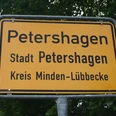 Ortsschild Petershagen Ortsschild der Stadt Petershagen im Kreis Minden-Lübbecke, umgeben von grünen Blättern.
