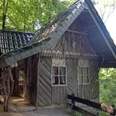 Märchenwald Holzhütte im Wald, mit altem Holzschindeldach, umgeben von Bäumen, rustikaler Charme.