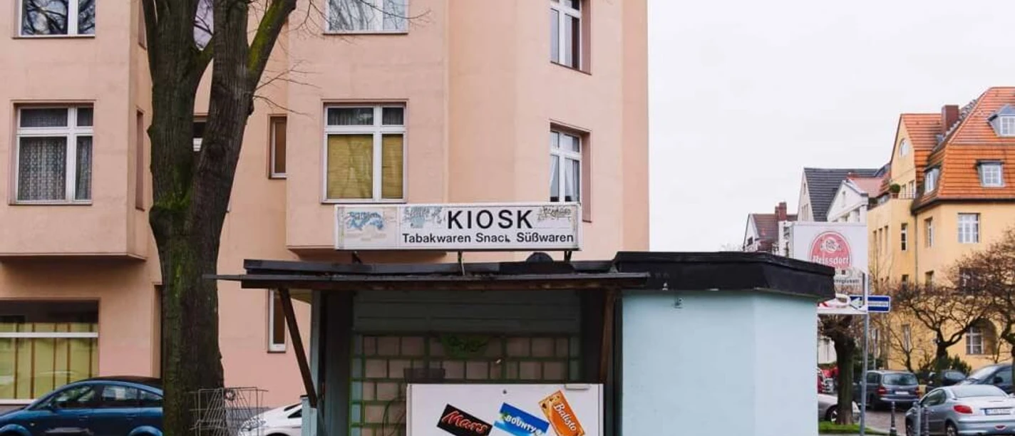 Kiosk at Nikolausplatz Small kiosk on a quiet street corner surrounded by residential buildings, featuring advertising boards for snacks.