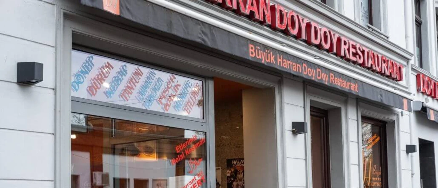 Büyük Harran Doy Doy Außenansicht eines türkischen Restaurants mit großen Fenstern und Pflanzen am Eingang.