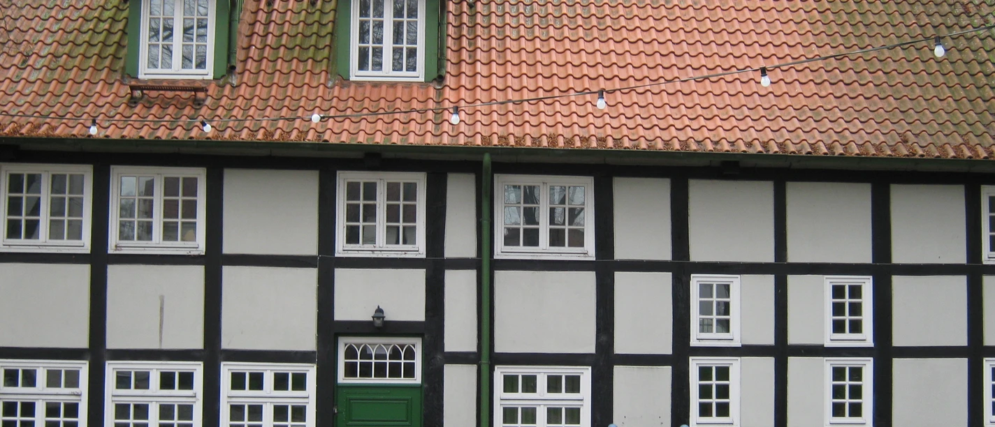 Fachwerkgebäude mit rotem Ziegeldach und grüner Tür, Stadtbücherei Preußisch Oldendorf.