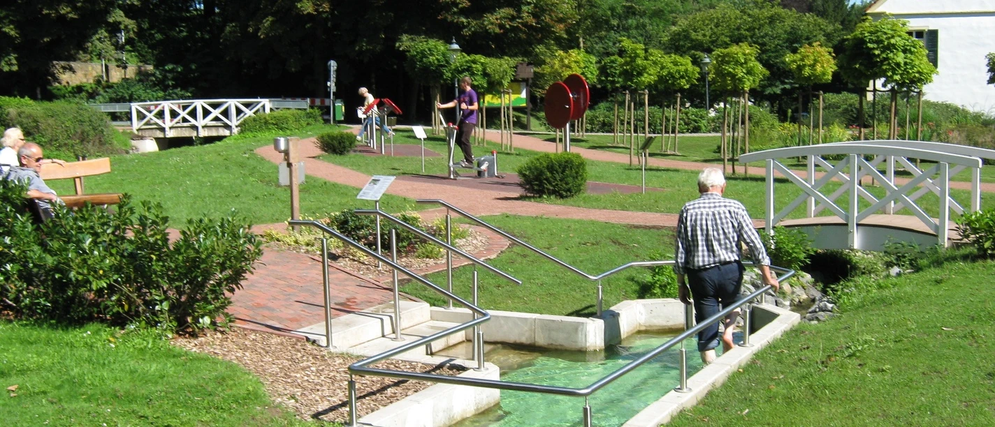 Wassertretbecken im Kurpark Bad Holzhausen Eine Person nutzt das Wassertretbecken im Kurpark Bad Holzhausen bei sonnigem Wetter.