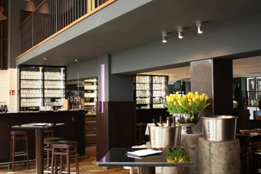 Henne Weinbar Schlicht und elegant eingerichtetes Restaurant mit grauen Wänden und dunklen Möbeln.