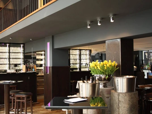 Henne Weinbar Schlicht und elegant eingerichtetes Restaurant mit grauen Wänden und dunklen Möbeln.A simple and elegantly furnished restaurant with gray walls and dark furniture.