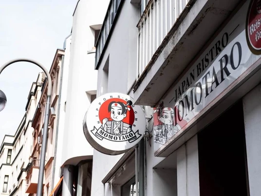 Momotaro Fassade eines Gebäudes in Köln mit dem japanischen Bistro Schild "Momotaro" an der Außenwand.Facade of a building in Cologne with the Japanese bistro sign ‘Momotaro’ on the outer wall.