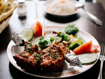 Ginti Nahaufnahme von einem Teller mit gebackenen Hähnchenschenkel und Salat.Close-up of a plate of baked chicken legs and salad.