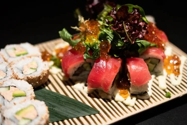 Zen Eine Auswahl an Sushi, darunter Nigiri und Maki, sorgfältig auf einem Bambusbrett arrangiert.