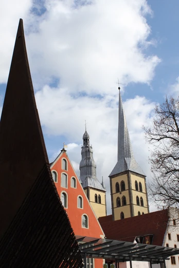 Historische Gebäude mit markanten Türmen erheben sich unter einem klaren Himmel in einer Altstadt.