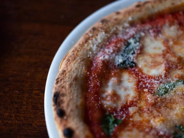 Trattoria Amalfi Rustic wooden surface, topped with a rectangular freshly-baked pizza featuring a crispy crust and melted cheese.