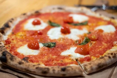 NeoNeo Eine knusprige Pizza Margherita mit leuchtend roten Tomaten, flüssigem Mozzarella und frischem Basilikum.