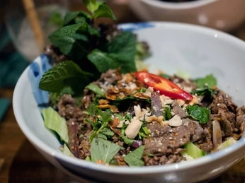 Restaurant Lua by Danny Nahaufnahme von einem vietnamesischen Gericht, bestehend aus Rindfleischstückchen, frischer Minze und Erdnüssen.Close-up of a Vietnamese dish consisting of pieces of beef, fresh mint, and peanuts.