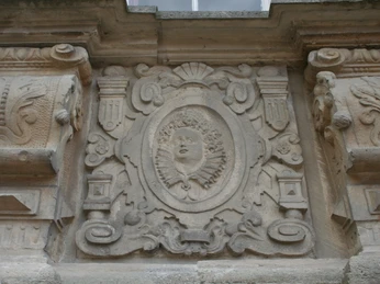 Steinernes Relief einer Person mit Halskrause, eingefasst von dekorativen Ornamenten.