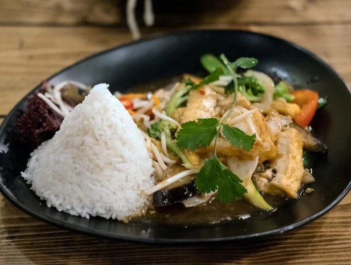 Restaurant Ha Noi 46 Ein asiatisches Gericht mit Reis auf schwarzem Teller.An Asian dish with rice on a black plate.