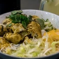 Nam La Vietnamienne Cuisine Eine kunstvoll arrangierte vietnamesische Schale mit Reisnudeln, knusprig gebratenem Tofu und frischen Kräutern auf Reisnudeln, garniert mit knackigem Gemüse.An artfully arranged Vietnamese bowl with rice noodles, crispy fried tofu and fresh herbs on rice noodles, garnished with crunchy vegetables.