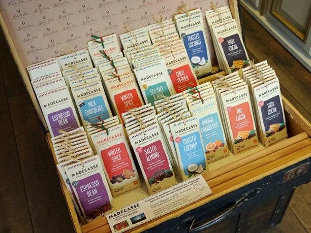Hernando Cortez Chocolates A wooden case presents various types of Madecasse chocolate in creative packaging.