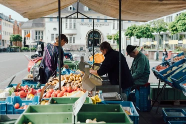Wochenmarkt auf dem Neptunplatz Marktstände auf dem Neptunplatz in Köln unter einem großen Pavillon. Menschen kaufen frisches Obst und Gemüse.