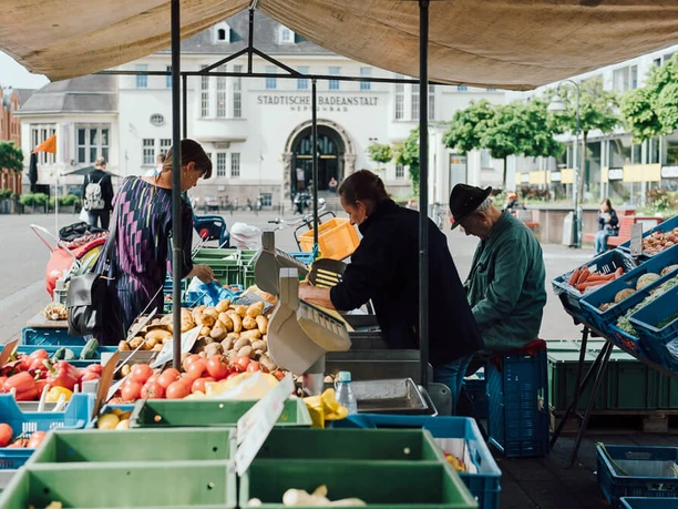 Wochenmarkt auf dem Neptunplatz Marktstände auf dem Neptunplatz in Köln unter einem großen Pavillon. Menschen kaufen frisches Obst und Gemüse.
