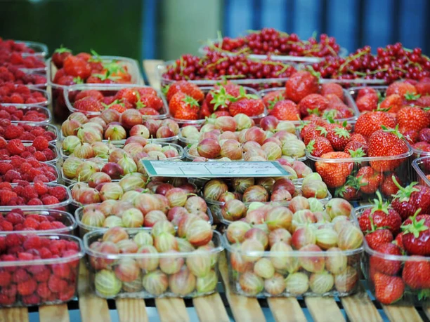 Wochenmarkt in Deutz Frisches Obst, darunter Erdbeeren, Himbeeren und Stachelbeeren, auf einem Holztisch präsentiert.